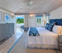 Stylish guest bedroom at Coconut Grove 2 featuring a king-size bed, elegant blue-themed decor, en-suite bathroom, and private terrace with garden views.
