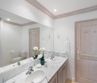 Luxurious en-suite master bathroom at Forest Hills 23, Barbados, with a dual-sink vanity, marble countertops, and a spacious mirror.