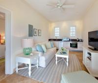 Cozy living area in the guest cottage at Howzat Villa, Royal Westmoreland, Barbados, featuring a kitchenette, plush seating, and bright Caribbean decor.