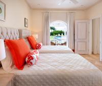 Elegant bedroom in the guest cottage at Howzat Villa, Barbados, with twin beds, bright decor, and direct access to the poolside patio.