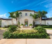Grand entrance of Howzat Villa, Royal Westmoreland, Barbados, surrounded by lush tropical landscaping and elegant colonial-style architecture.