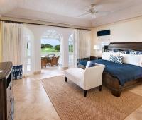 Elegant master bedroom at Howzat Villa, Barbados, featuring a king-size bed, private terrace, and breathtaking golf course and ocean views.