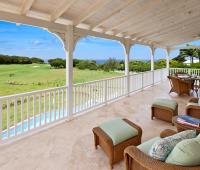 Spacious upstairs patio at Howzat Villa, Barbados, with comfortable lounge seating and panoramic golf course and ocean views.