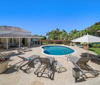 Private pool deck with sun loungers, umbrellas, and lush tropical gardens at Ixora, Royal Westmoreland, Barbados