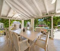 Open-plan dining area with elegant furniture and a stunning view of the pool at Ixora Royal Westmoreland, Barbados