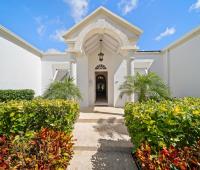 Walkway to the main entrance of Ixora Villa, lined with neatly trimmed hedges and colorful tropical flowers
