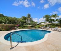 Serene poolside at Ixora, Royal Westmoreland, Barbados with lush gardens, blue skies, and sunbeds by the pool