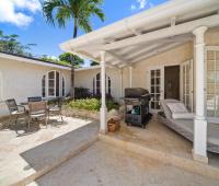Relaxing outdoor space at Ixora with a BBQ grill, chairs, and a small palm tree, perfect for enjoying the tropical climate at Royal Westmoreland, Barbados