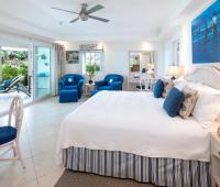 A tranquil master bedroom at Palm Beach 101 in Barbados, featuring a king-size bed, stylish coastal decor, and direct access to a private patio.