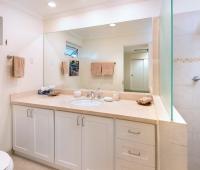 A contemporary en-suite bathroom at Palm Beach 101 in Barbados, offering a spacious walk-in shower, marble vanity, and soft lighting.