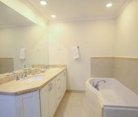 Luxurious master bathroom at Palm Beach 109, Barbados, featuring a double vanity, elegant stone countertops, and a soaking tub.