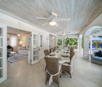 Covered outdoor dining area at Sandalwood House, Barbados, with seating for guests and easy access to the living room and pool.