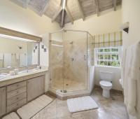 Spacious master bathroom at Sandalwood House, featuring a double vanity, glass-enclosed shower, and vaulted ceilings.