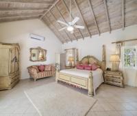 Luxurious primary bedroom at Sandalwood House with high vaulted ceilings, elegant furnishings, and a king-sized bed.