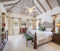 Second bedroom at Sandalwood House, featuring an ornate iron bed, vaulted ceilings, and stylish decor.