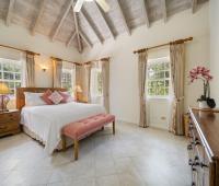 Third bedroom at Sandalwood House, featuring a king-sized bed, vaulted ceilings, and natural light from large windows.