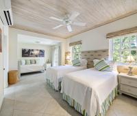 Bright and airy twin bedroom at Sandalwood House, with two beds, stylish striped cushions, and a seating area with garden views