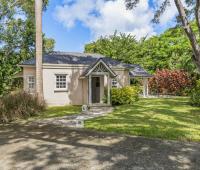 Charming garden cottage at Sandalwood House, nestled within the lush greenery, featuring a quaint gabled entrance