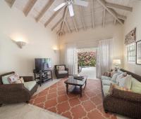 Guest Cottage living room at Sandalwood House, with high vaulted ceilings, wicker furnishings, and views of the garden through wide doors.