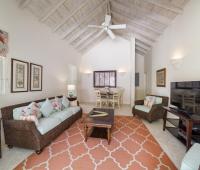 Spacious living and dining area at Cottage of Sandalwood House, with wicker furniture, vaulted ceilings, and a cozy dining nook