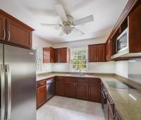 Fully equipped kitchen at Cottage of Sandalwood House, featuring rich wooden cabinetry, granite countertops, and stainless steel appliances.