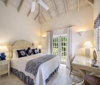 Cottage bedroom one at Sandalwood House with high vaulted ceilings, a king-sized bed, and elegant blue and white decor