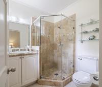 Cottage bathroom one at Sandalwood House with a glass-enclosed shower, neutral stone tiles, and a bright, airy design