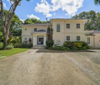 Grand entrance of Sandalwood House, framed by mature trees and tropical landscaping