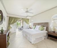 Elegant bedroom in Seabreeze Penthouse, Sugar Hill Resort, Barbados, with a comfortable queen-size bed, soft green accents, and direct access to a private balcony with views of tropical palm trees, creating a serene and restful atmosphere.