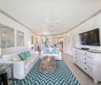 Coastal-themed living space in Seabreeze Penthouse, Sugar Hill Resort, Barbados, with white sofas, a unique driftwood coffee table, and turquoise accents, creating a relaxed yet refined environment ideal for unwinding.