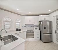 Modern kitchen in Seabreeze Penthouse, Sugar Hill Resort, Barbados, featuring stainless steel appliances, sleek white cabinetry, and a large sink, providing a functional and stylish space for cooking and entertaining.