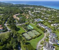 Expansive aerial view over Sugar Hill Resort and surrounding luxury estates in Barbados, with clear views of the resort’s central pool and tennis courts, and the stunning Caribbean Sea in the background.