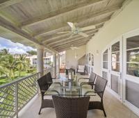 Private balcony of Seabreeze Penthouse at Sugar Hill Resort, Barbados, with outdoor dining area, wicker furniture, and ceiling fans, offering a relaxing space to enjoy views of the resort's lush gardens and Caribbean breezes.