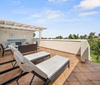 Rooftop terrace of Seabreeze Penthouse, Sugar Hill Resort, Barbados, featuring sun loungers, cozy seating area, and partial sea views, perfect for sunbathing or evening relaxation with picturesque surroundings.