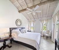 Master bedroom of Seabreeze Penthouse at Sugar Hill Resort, Barbados, with high vaulted ceilings, a plush king-size bed, and large windows that fill the space with natural light, offering a peaceful retreat overlooking the lush resort landscape.