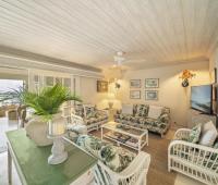 A bright and airy living room at Seascape beachfront villa in Barbados, furnished with tropical-inspired decor and direct access to the patio overlooking the Caribbean Sea, perfect for vacation rentals.