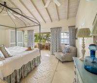 A luxurious master bedroom at Seascape villa in Barbados, featuring a four-poster bed, vaulted ceiling, and ocean views, creating a peaceful retreat for holiday rental guests.