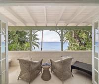 A private balcony at Seascape beachfront villa in Barbados, offering wicker seating and breathtaking views of the Caribbean Sea, perfect for relaxing mornings or sunset cocktails during a holiday rental.