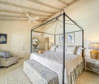 Image of the master bedroom with a four-poster bed at Seascape, Barbados: A bright, spacious master bedroom featuring a stunning four-poster bed, vaulted ceilings, and stylish decor, exuding Caribbean charm and providing a tranquil retreat in this luxury Barbados holiday villa.