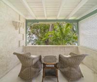 Image of a private balcony overlooking lush greenery at Seascape, Barbados: A private balcony adorned with wicker seating, overlooking lush tropical gardens and offering a peaceful retreat for morning coffee or evening relaxation during your stay at Seascape, Barbados.