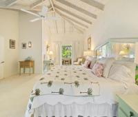 Image of the tropical-themed bedroom at Seascape, Barbados: A bright and airy bedroom with tropical-inspired decor, featuring a palm tree quilt and natural light flooding through large windows, enhancing the cozy Caribbean vibe at this beachfront Barbados villa.