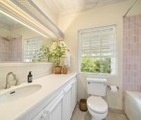 Image of the en-suite bathroom with a garden view at Seascape, Barbados: A modern en-suite bathroom with soft pink tiles, a large vanity, and a window that frames the lush greenery outside, creating a tranquil retreat for guests in this Barbados holiday villa.