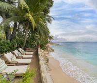 Sun loungers on the private beach at Seascape, Barbados, shaded by swaying palm trees and offering unmatched relaxation for holiday rental guests seeking luxury and tranquility.