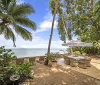 The beachfront patio at Seascape, Barbados, featuring a dining area, sun loungers, and tropical gardens, provides a perfect space for enjoying luxury villa rentals with direct beach access.