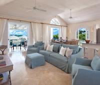 The bright and airy living room of Sugar Cane Ridge 12 features plush seating, high ceilings, and seamless indoor-outdoor flow to a covered terrace with golf views