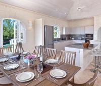 A beautifully designed dining area with elegant wooden furnishings and an open-plan modern kitchen at Sugar Cane Ridge 12, Royal Westmoreland, Barbados.