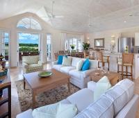 Elegant open-plan living space with high ceilings, plush seating, and a modern kitchen at Sugar Cane Ridge 22, Royal Westmoreland.