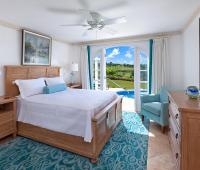 Serene master bedroom with a king-sized bed, pool access, and lush golf course views at Sugar Cane Ridge 22, Royal Westmoreland.