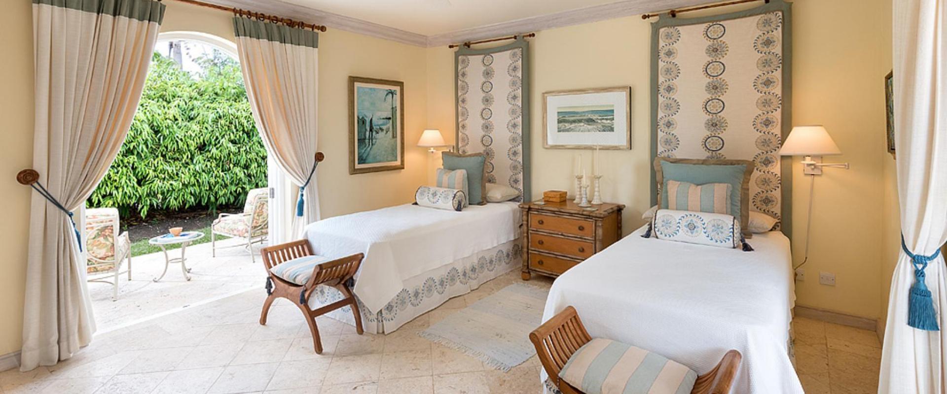 Beautifully designed twin bedroom with soft blue and cream accents, garden views, and direct outdoor access at Benjoli Breeze, Royal Westmoreland.