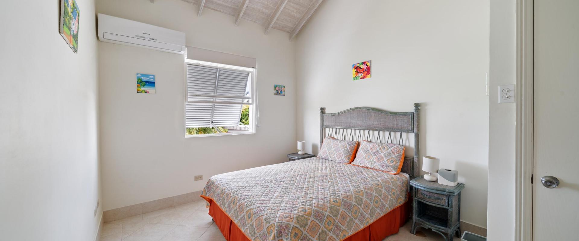 Cozy second bedroom with air conditioning, vaulted ceiling, and queen bed at Blue Waters 1, a private holiday home near Miami Beach Barbados.